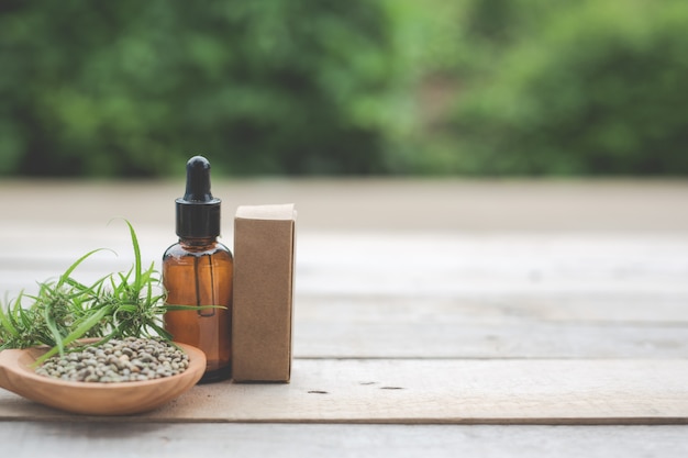 Free photo cannabis, cannabis seeds, cannabis oil placed on a wooden floor with a green tree  in the background.