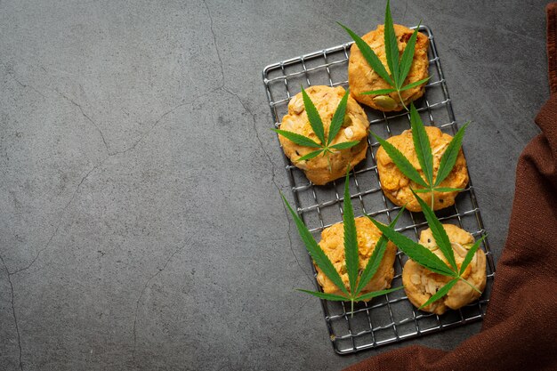 Cannabis cookies and cannabis leaves put on dark floor