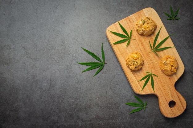 Cannabis cookies and cannabis leaves put on wooden cutting board