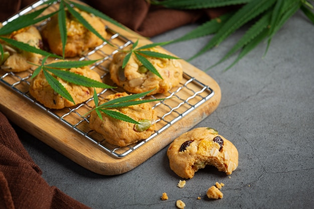 Cannabis cookies and cannabis leaves put on wooden cutting board