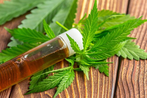 Cannabis leaves and oil on wooden background