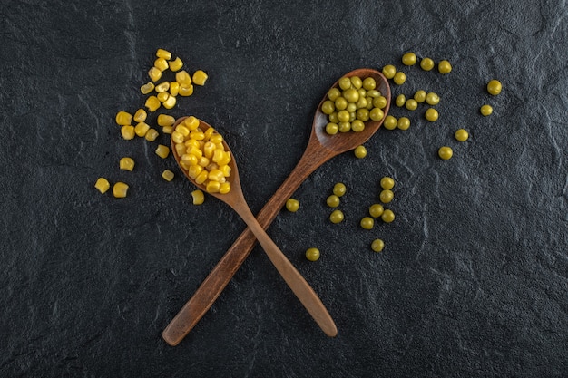 Canned corns and green peas with spoons.