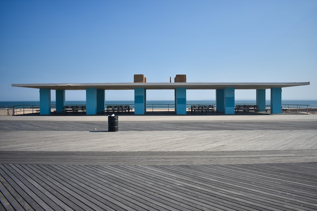 Canopy building at the beach with blue columns, white roof and benches