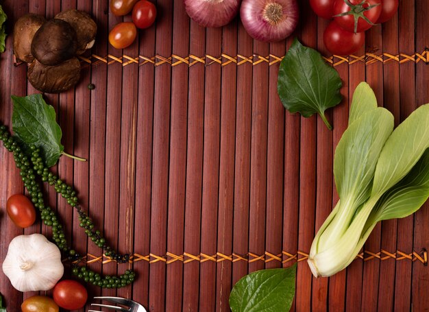 Cantonese lettuce, fresh pepper seeds, garlic, tomatoes, shiitake mushrooms, and red onions placed on wooden boards