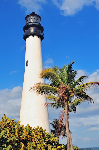 Cape Florida Light lighthouse with Atlantic Ocean and palm tree at beach in Miami with blue sky and cloud.