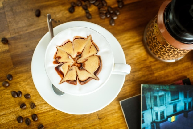 新鮮なコーヒー豆の水と茶色の背景の本とカプチーノ