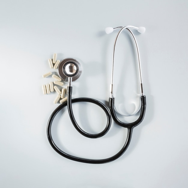 Capsules with stethoscope on grey background