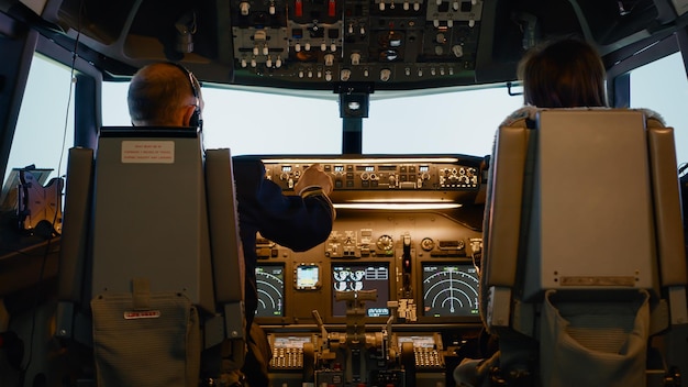 Free photo captain and woman copilot in cockpit preparing to fly airplane, using dashboard command buttons to fix altitude and longitude control to takeoff. aerial navigation with radar compass.