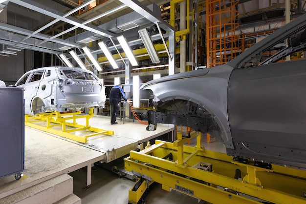 Car bodies are on assembly line Factory for production of cars Modern automotive industry A car being checked before being painted in a hightech enterprise