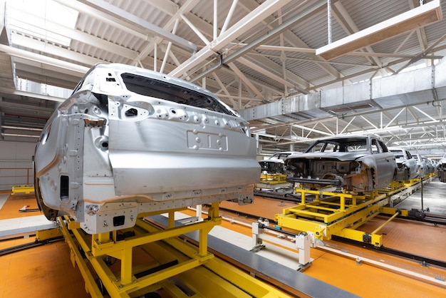 Car bodies are on assembly line Factory for production of cars Modern automotive industry A car being checked before being painted in a hightech enterprise