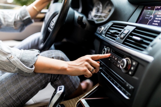 Car dashboard. Radio closeup. Woman sets up radio while driving car