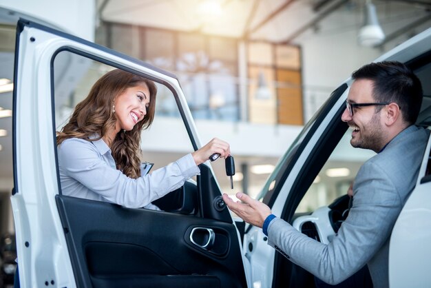 Car dealer and customer at vehicle showroom choosing new car