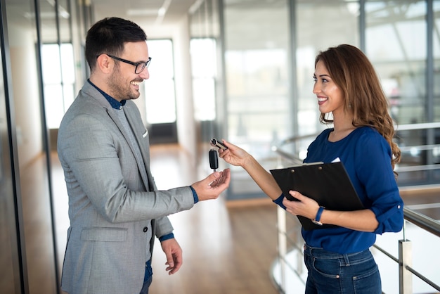 Car dealer handing over keys to the vehicle buyer