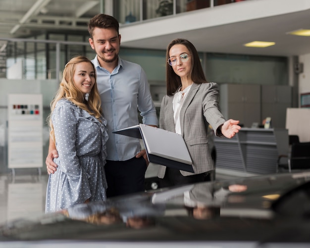 Free photo car dealer showing a automobile to a couple