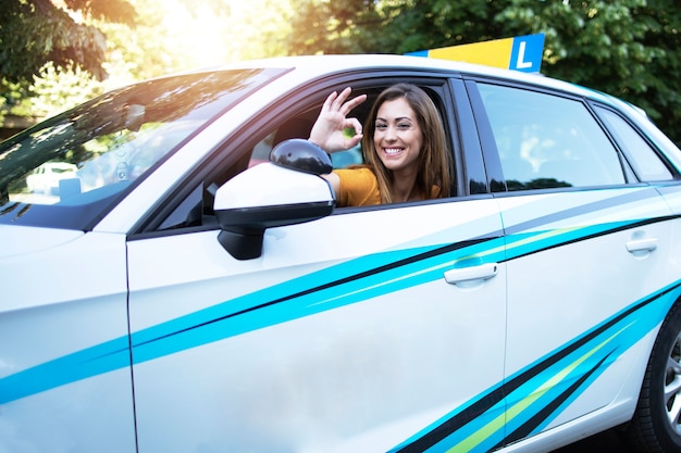 Car driving student showing okay gesture sign and sitting at vehicle driver position