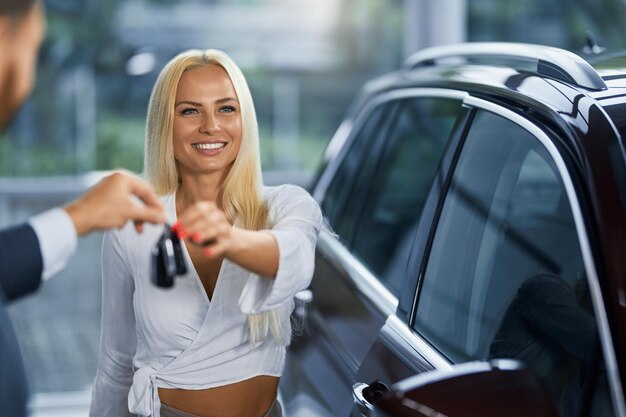 쇼룸에서 여성 구매자에게 열쇠를 주는 자동차 관리자