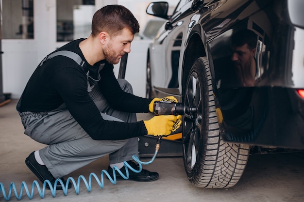 Car mechanic changing wheels in car