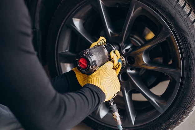 Free photo car mechanic changing wheels in car