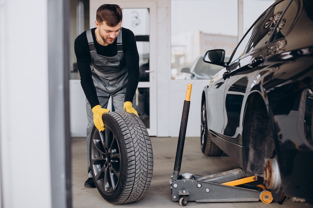 Car mechanic changing wheels in car