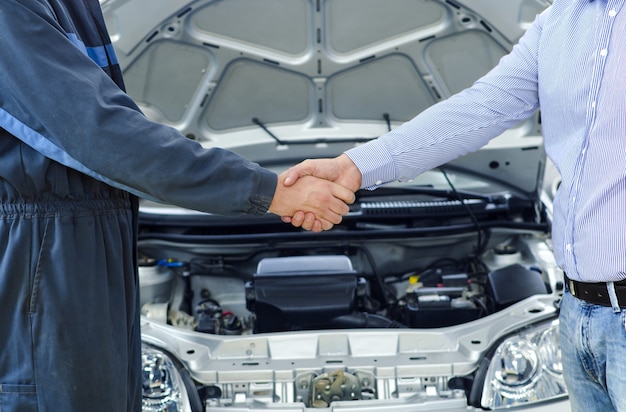 Car mechanic and customer shaking hands