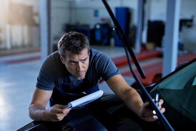 Free photo car mechanic examining vehicle problems while working at auto repair shop