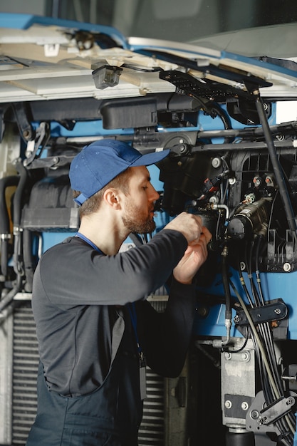 Car mechanic repairs blue car in garage with tools