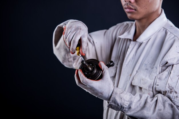 Car mechanic wearing a white uniform stand holding wrench