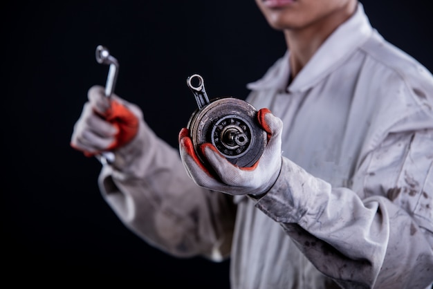 Car mechanic wearing a white uniform stand holding wrench