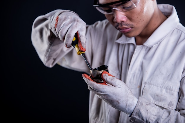 Free photo car mechanic wearing a white uniform stand holding wrench