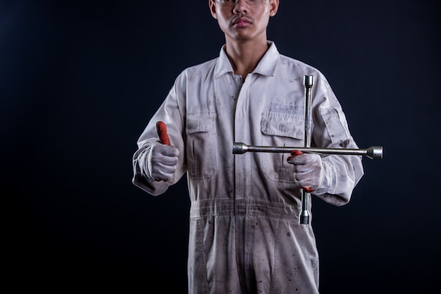 Free photo car mechanic wearing a white uniform stand holding wrench