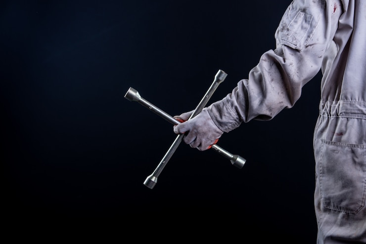 Free Photo car mechanic wearing a white uniform stand holding wrench