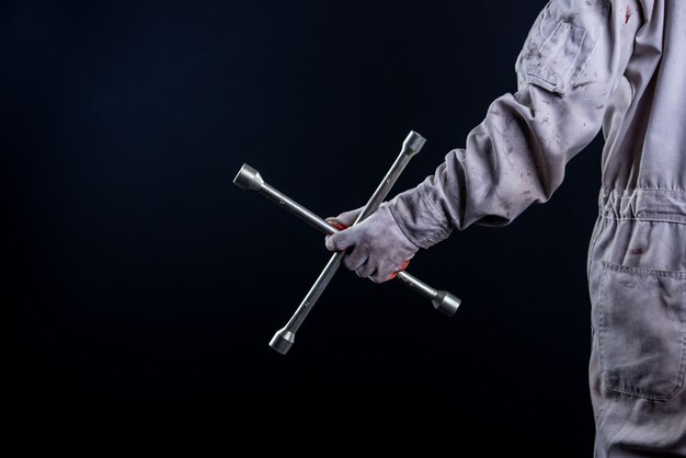 Car mechanic wearing a white uniform stand holding wrench