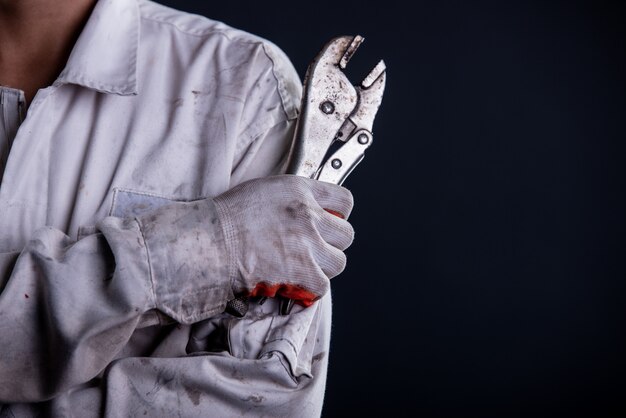 Car mechanic wearing a white uniform stand holding wrench