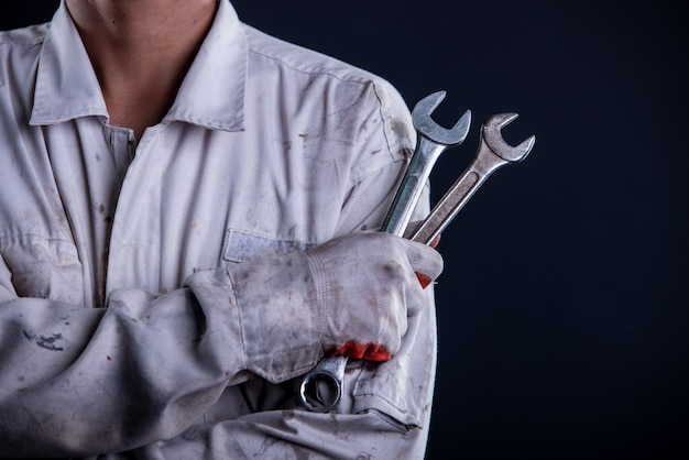 Car mechanic wearing a white uniform stand holding wrench