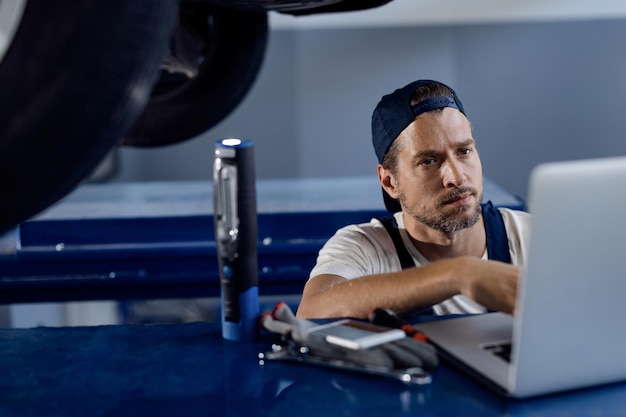 Car mechanic working on laptop at auto repair shop