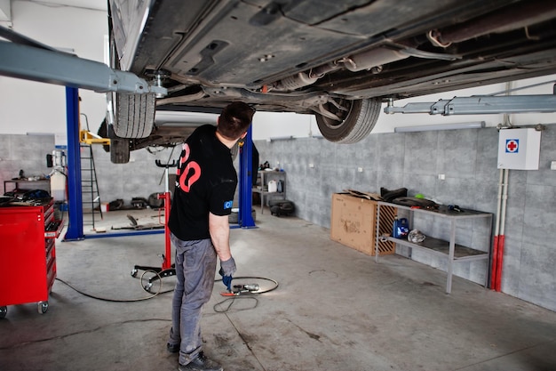 Тема ремонта и обслуживания автомобилей Механик в форме, работающий в автосервисе