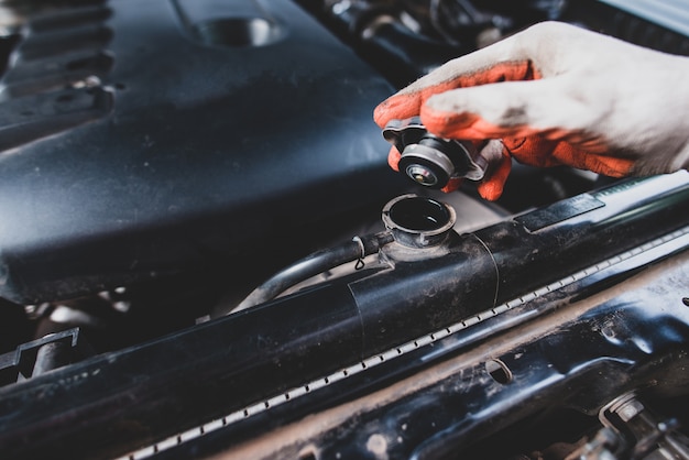 Car repairman wearing a white uniform standing and holding a wrench that is an essential tool for a mechanic