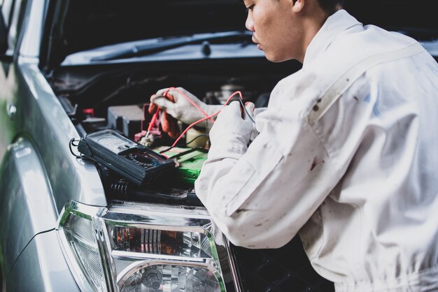 Car repairman wearing a white uniform standing and holding a wrench that is an essential tool for a mechanic