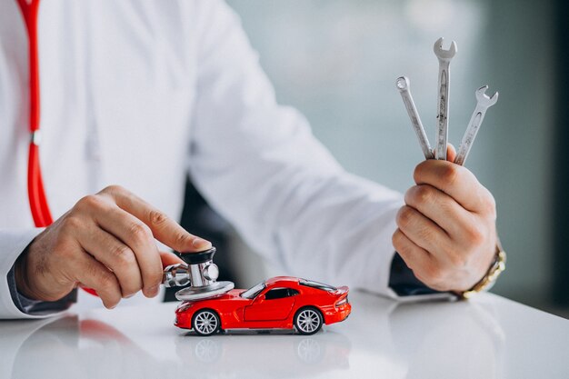 car technician with stethoscope in a car showroom