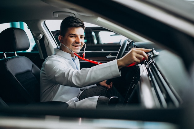 car technician with stethoscope in a car showroom