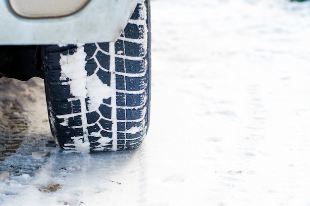 雪に覆われた冬の道にカータイヤ。降雪時の朝の雪路の車