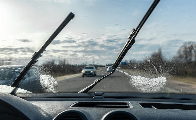 화창한 날씨에 운전할 때 자동차 와이퍼가 앞 유리를 청소합니다.