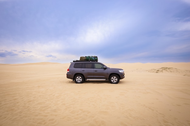 Car with baggage on top of it in the desert under a cloudy sky at daytime