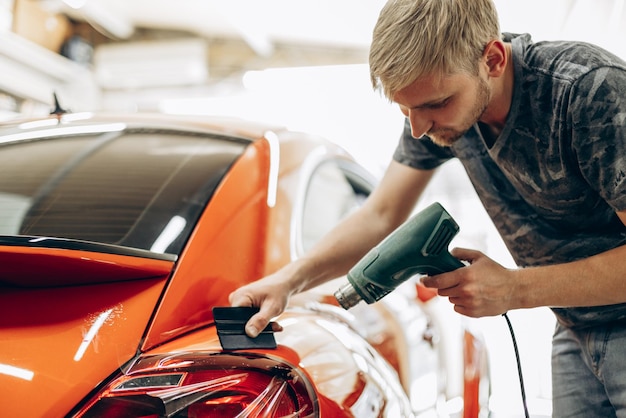 Free photo car wrapping with foil and drying with fan at car service