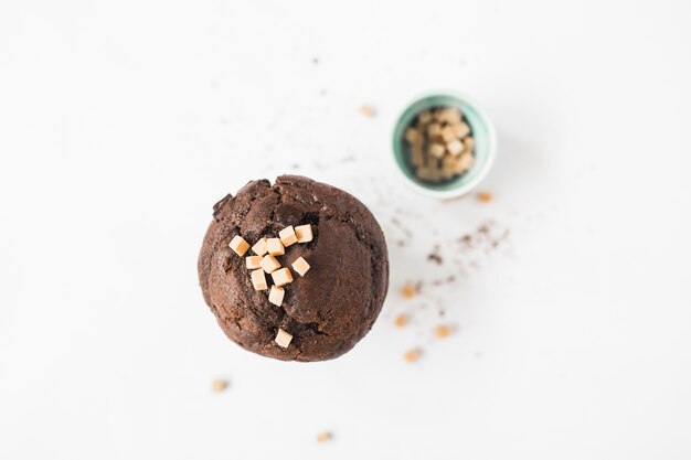 Caramel candies on chocolate cupcake against white background