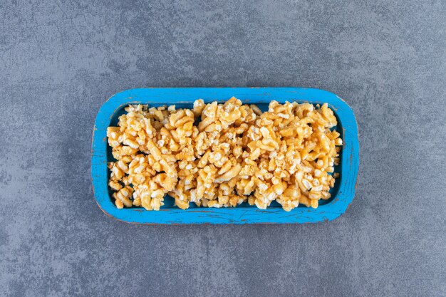 Caramel candies in a wooden plate, on the marble background.