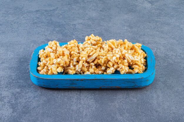 Caramel candies in a wooden plate, on the marble surface