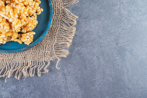 Caramel candies in a wooden plate on a texture, on the marble background.