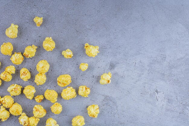 Caramel coated popcorn scattered over on marble surface