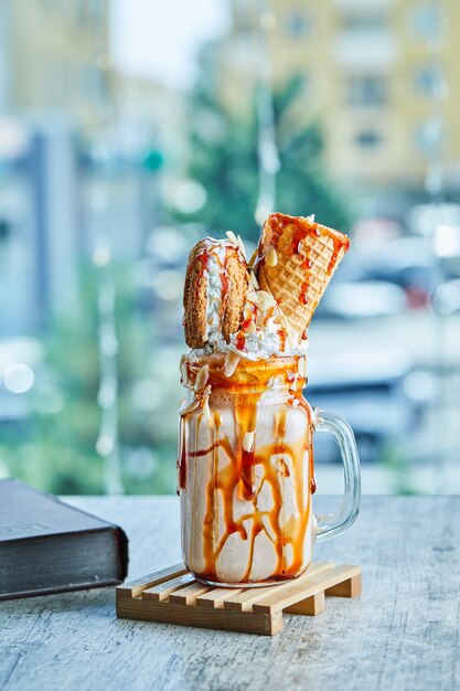 Caramel ring milkshake on the wooden plate with book .